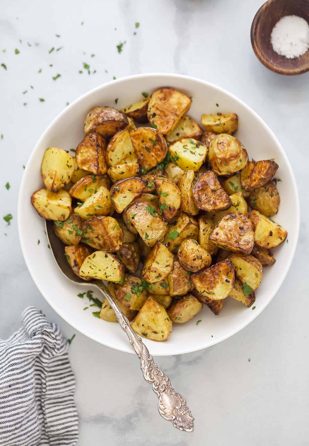 These are the best Air Fryer Roasted Potatoes! Tender on the inside and crispy on the outside. These potatoes are herby and delicious. a bowl of air fryer roasted potatoes