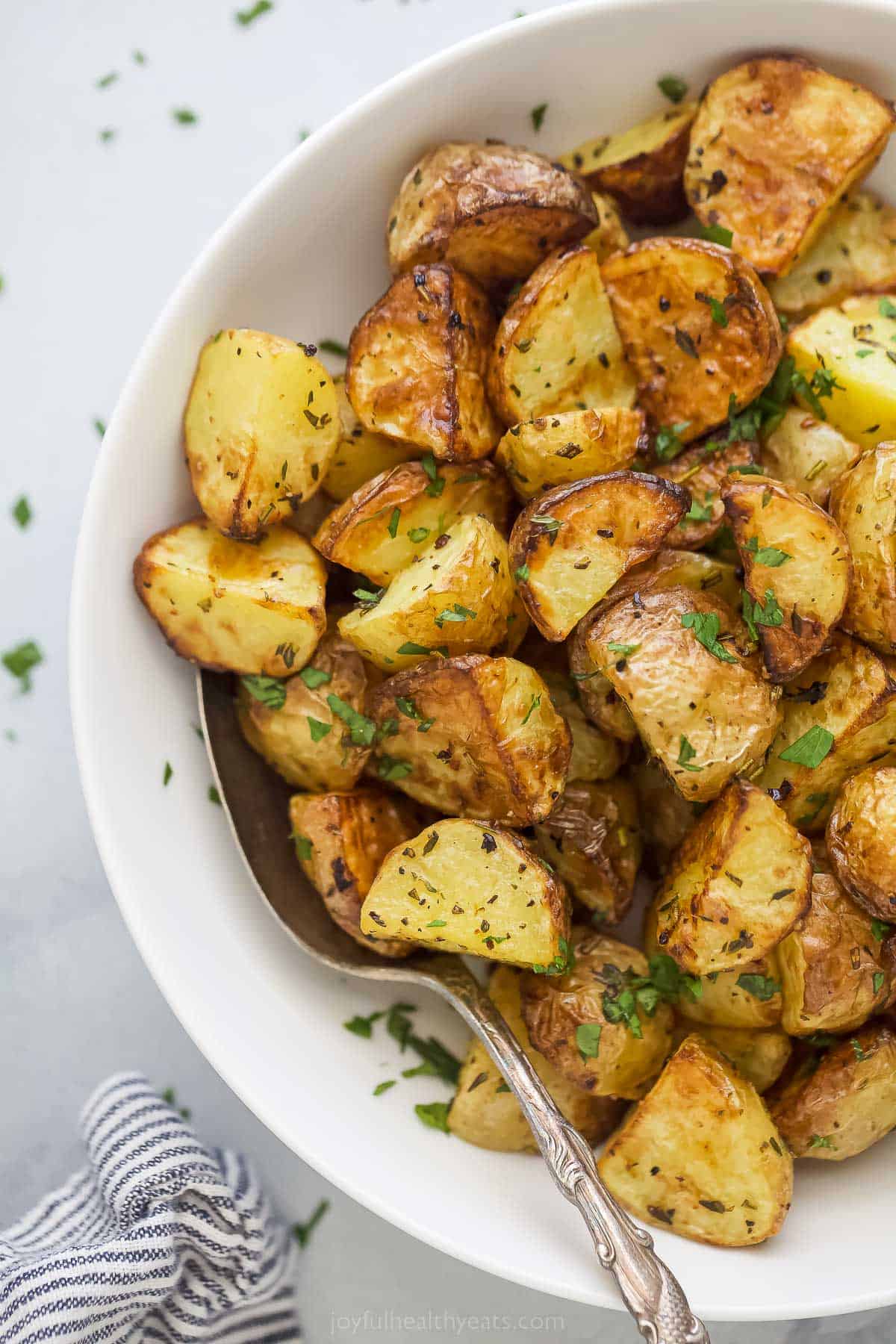 These are the best Air Fryer Roasted Potatoes! Tender on the inside and crispy on the outside. These potatoes are herby and delicious. a bowl of air fryer roasted potatoes