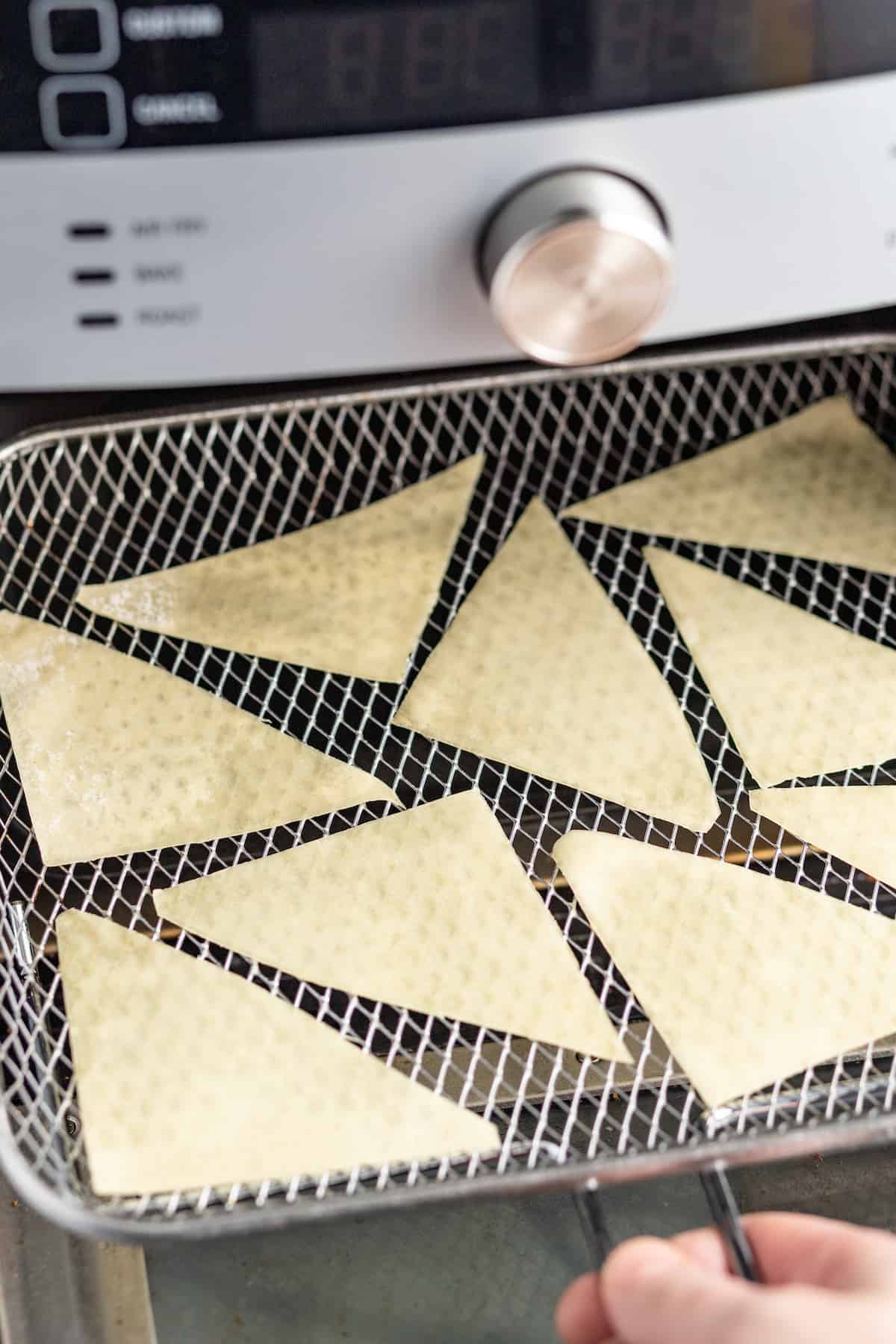 wonton triangles on a rack going into an air fryer