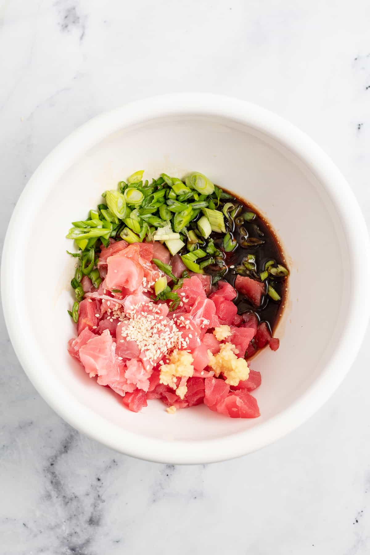 diced tuna in a bowl with various seasonings to make poke