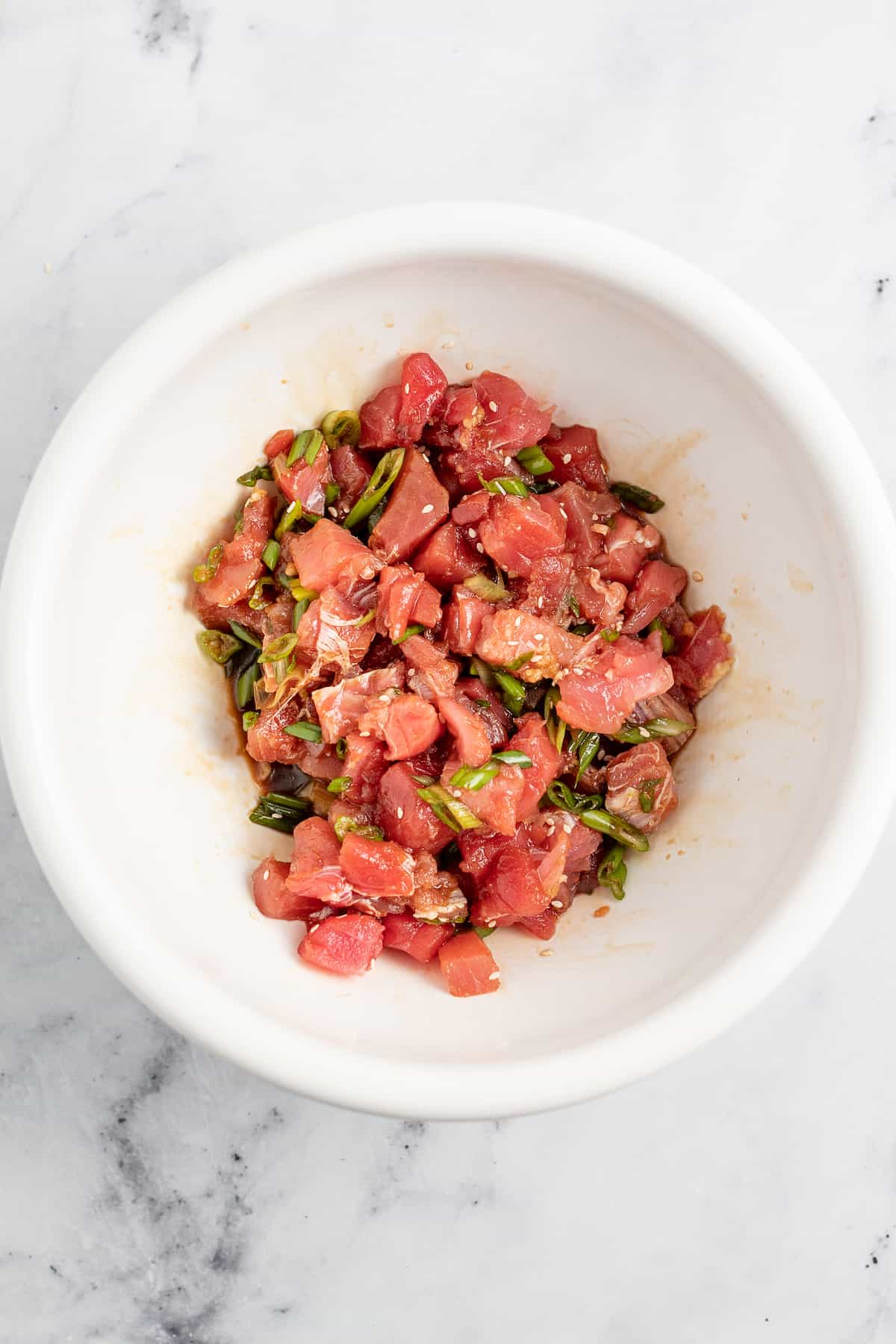 diced tuna in a bowl with various seasonings to make poke