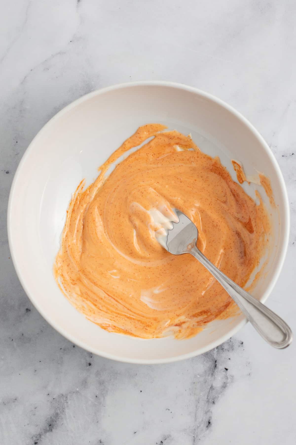 orange colored sauce in a white bowl with a fork