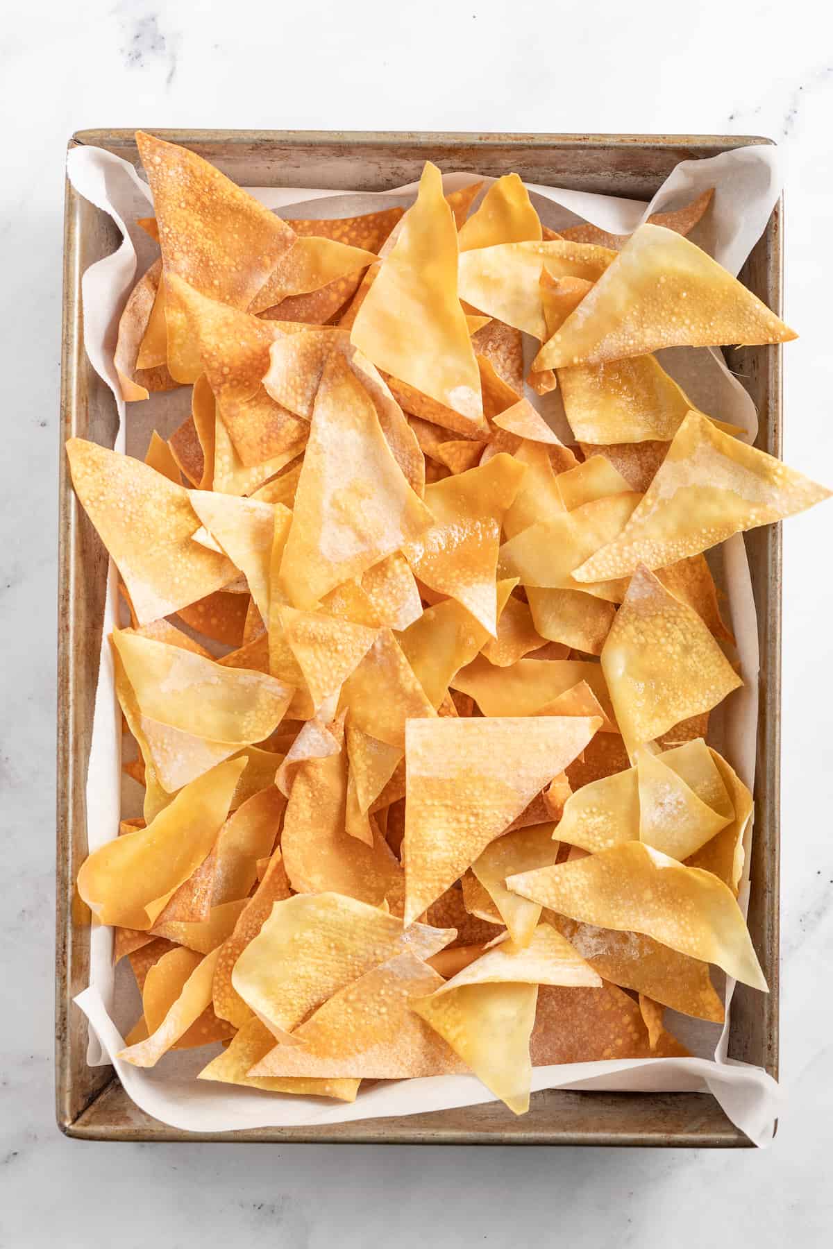 a sheet tray lined with parchment paper and fried wonton chips