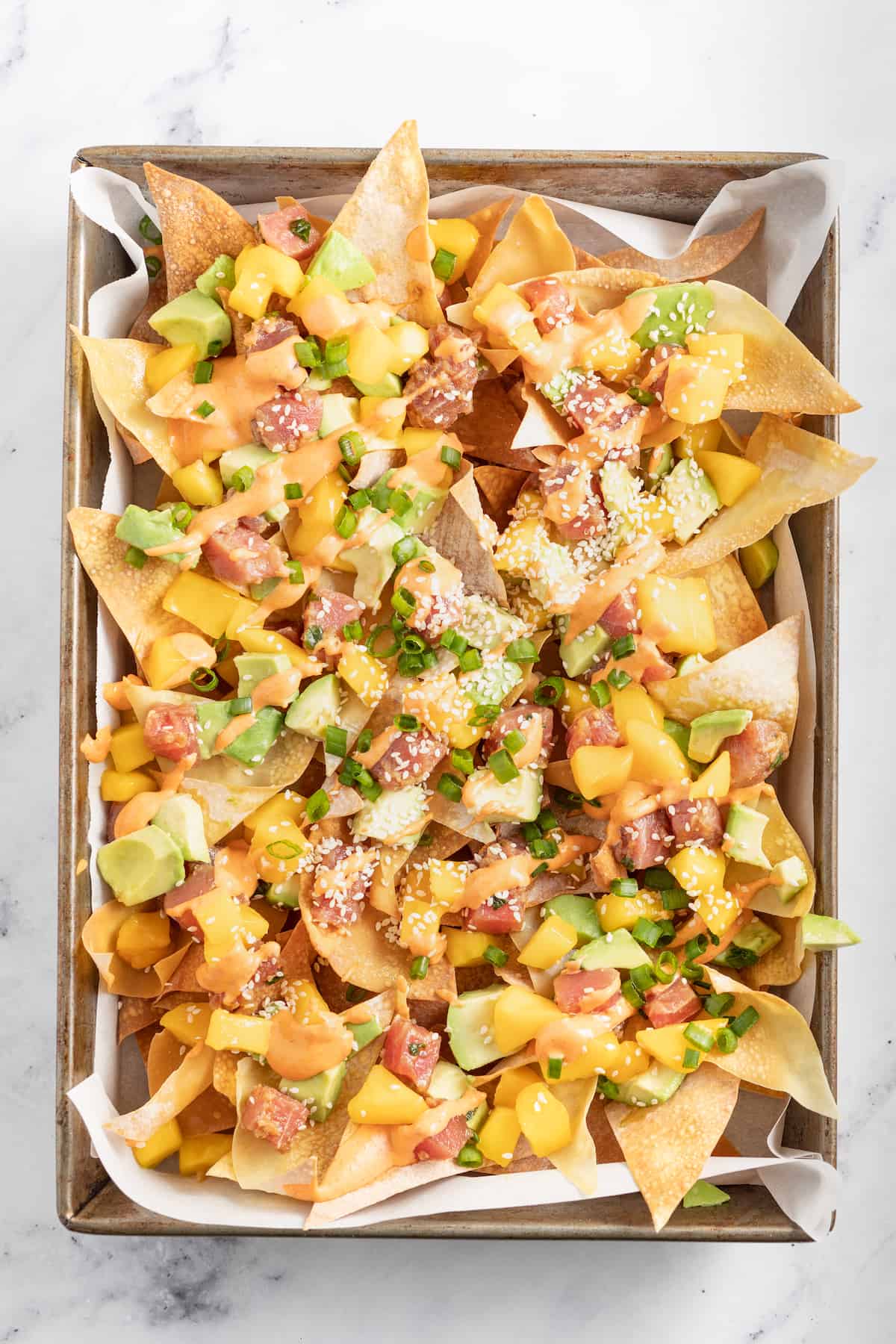 a platter of wonton chips topped with diced ahi tuna, mango, scallions, and sriracha mayo