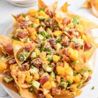 a plate of ahi tuna poke nachos with diced mango, green onions, and sriracha mayo