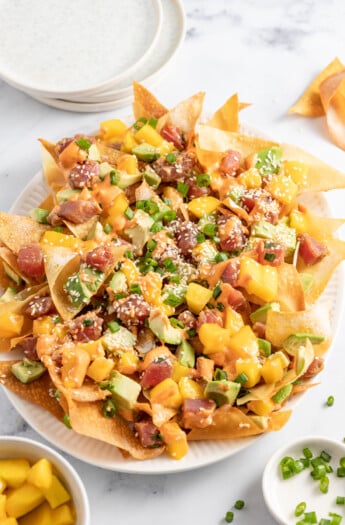 a plate of ahi tuna poke nachos with diced mango, green onions, and sriracha mayo