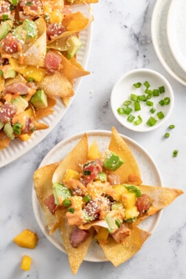 a plate of ahi tuna poke nachos with diced mango, green onions, and sriracha mayo