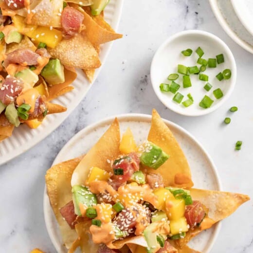 a plate of ahi tuna poke nachos with diced mango, green onions, and sriracha mayo