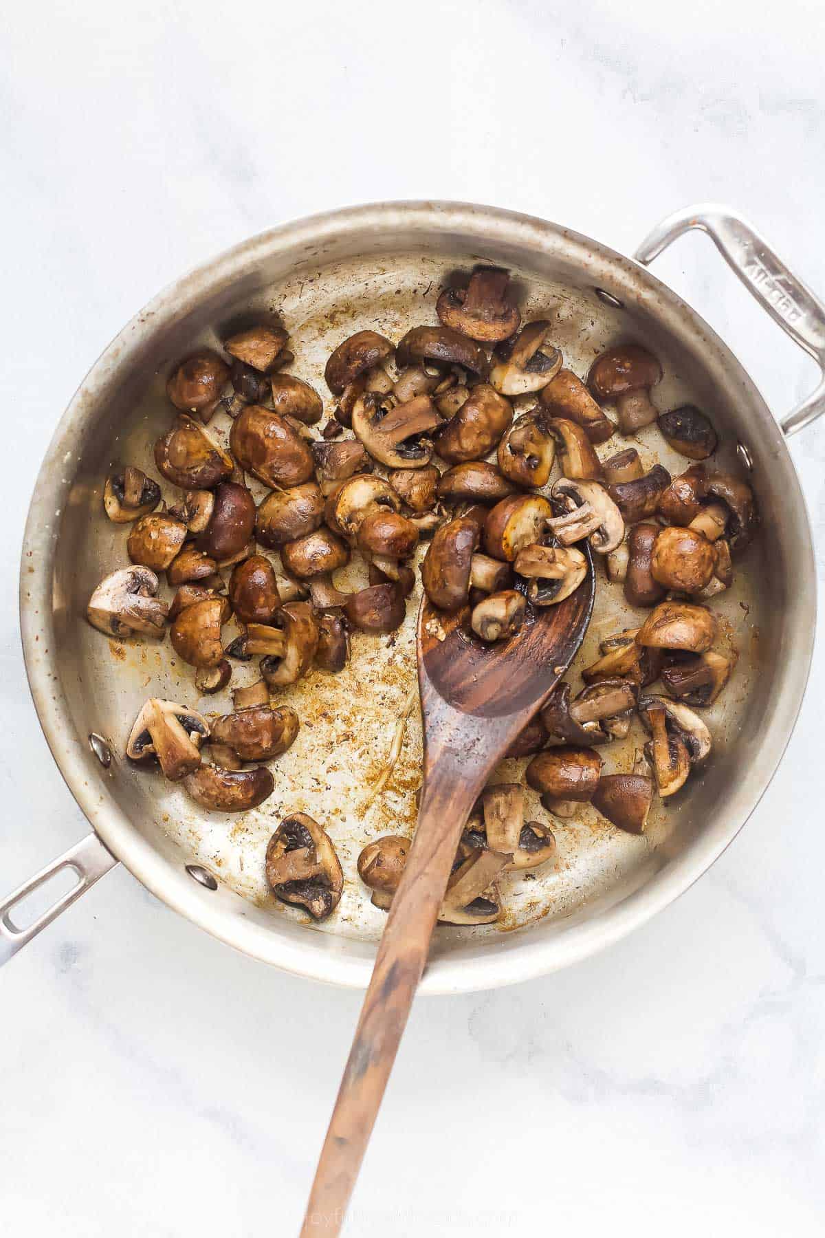 cooking mushrooms in a stainless steel pan