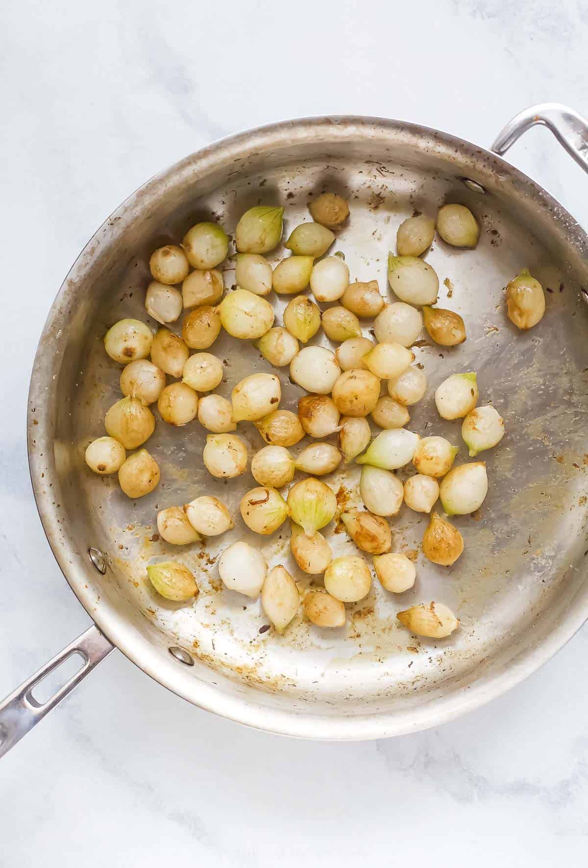 cooking pearl onions in a stainless steel pan