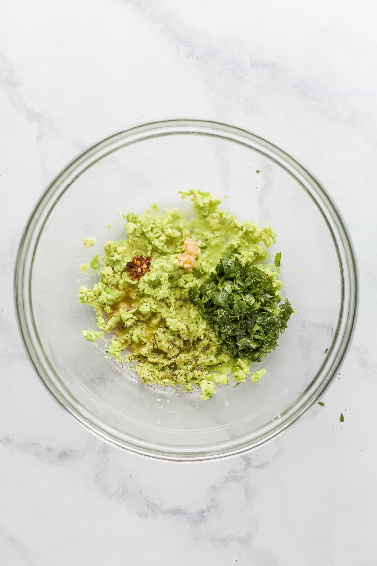 This Creamy Coleslaw for Fish Tacos is made with avocado instead of mayo. The smooth avocado-based dressing has cilantro, garlic, and lime. mixing ingredients into smashed avocado in a bowl
