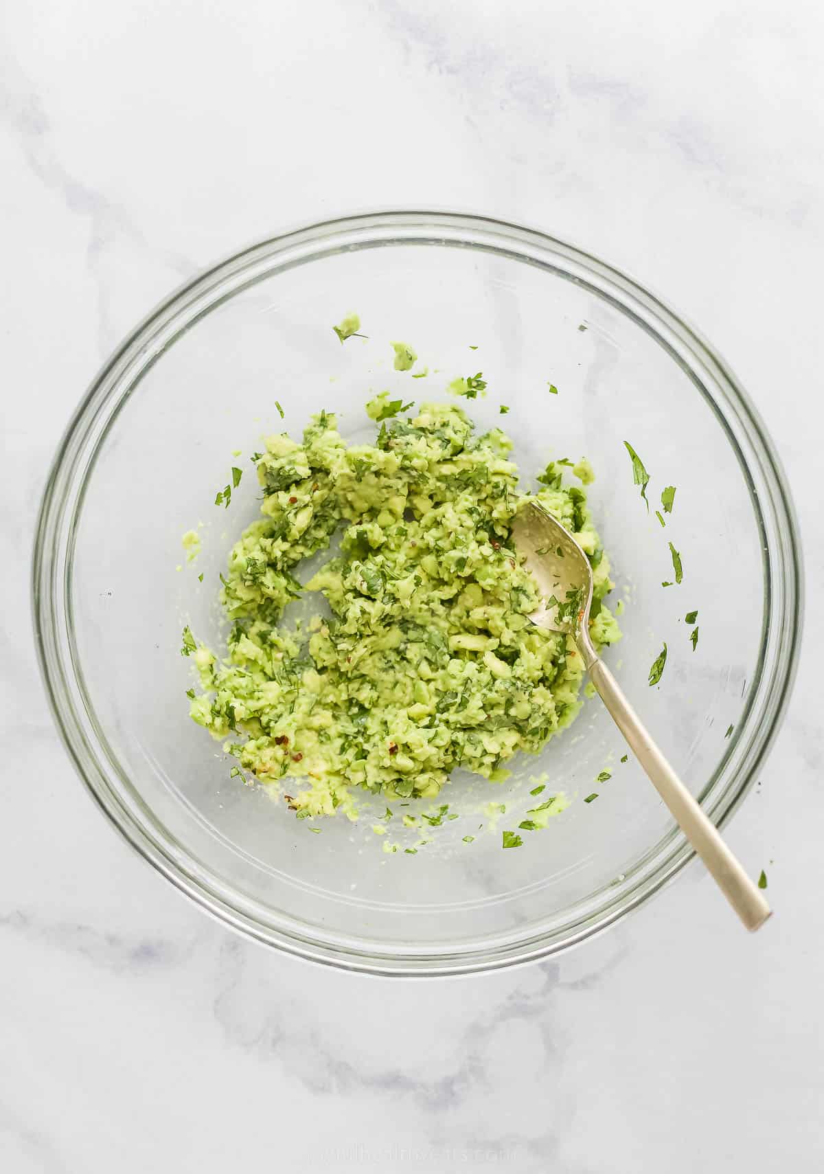 mashing avocado in a glass bowl