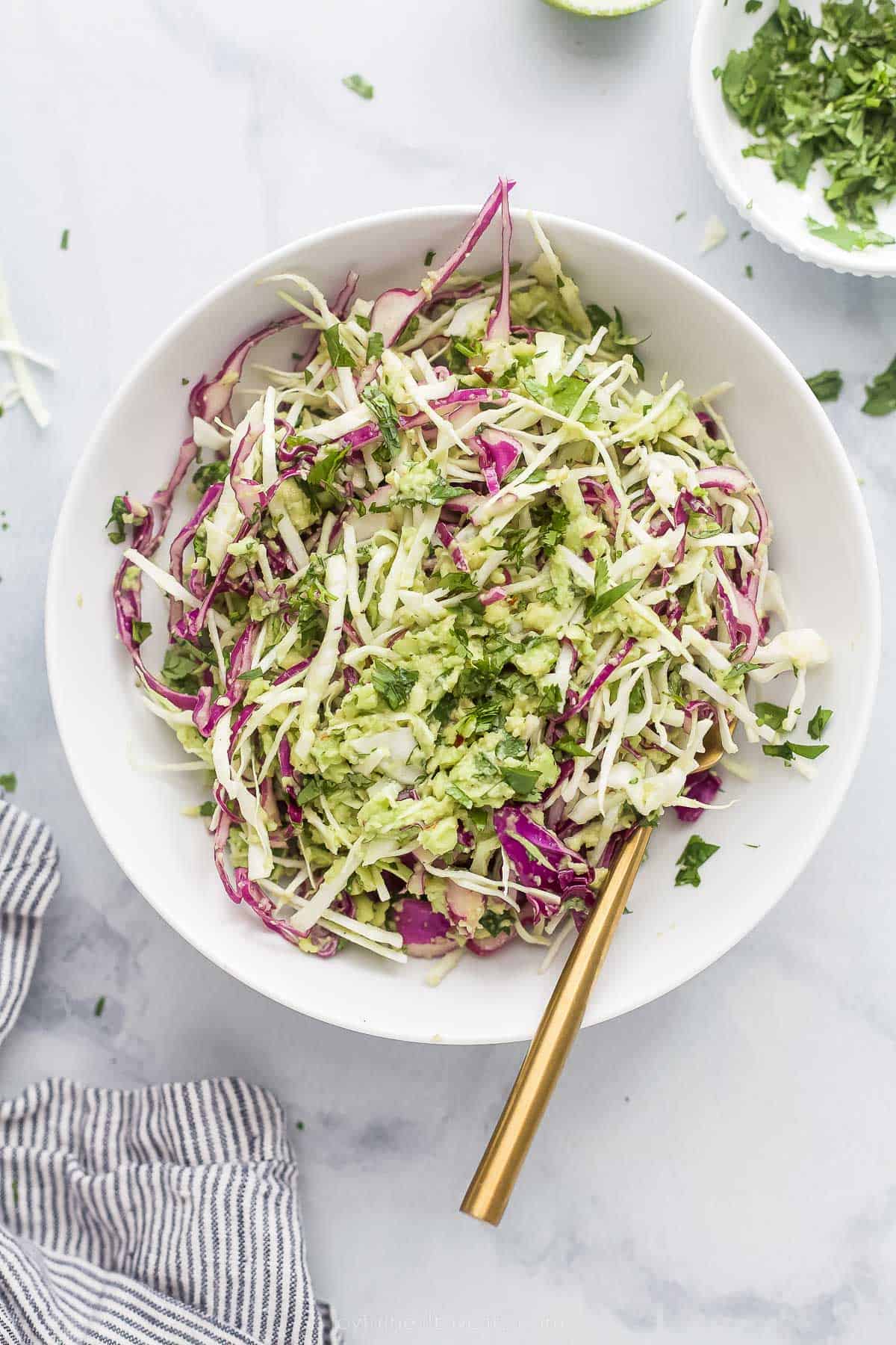 This Creamy Coleslaw for Fish Tacos is made with avocado instead of mayo. The smooth avocado-based dressing has cilantro, garlic, and lime. shredded creamy coleslaw for fish tacos in a bowl