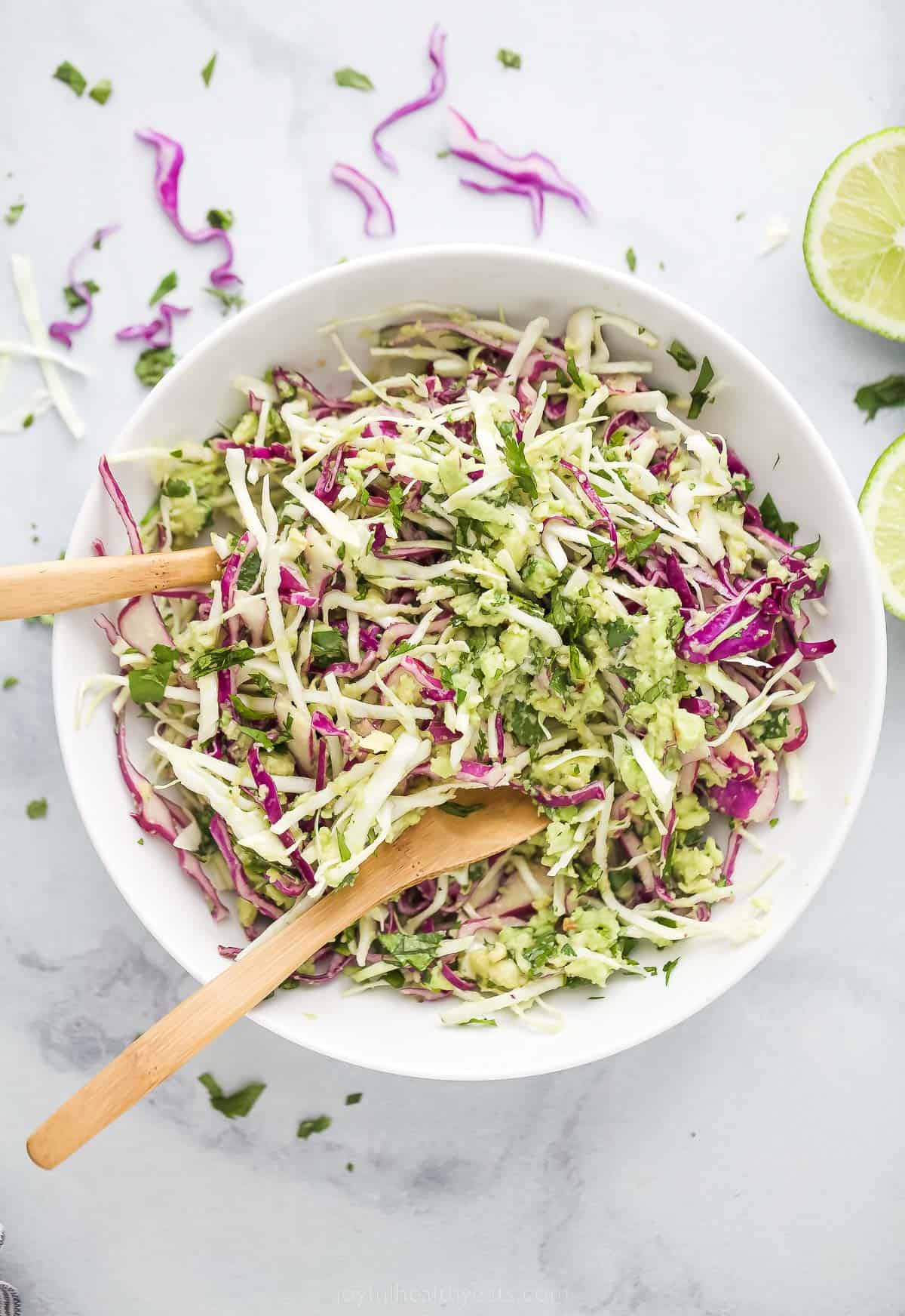 This Creamy Coleslaw for Fish Tacos is made with avocado instead of mayo. The smooth avocado-based dressing has cilantro, garlic, and lime. shredded creamy coleslaw for fish tacos in a bowl