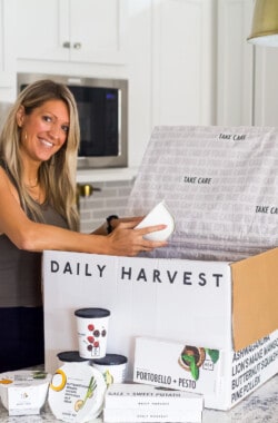 girl in workout clothes opening a daily harvest box