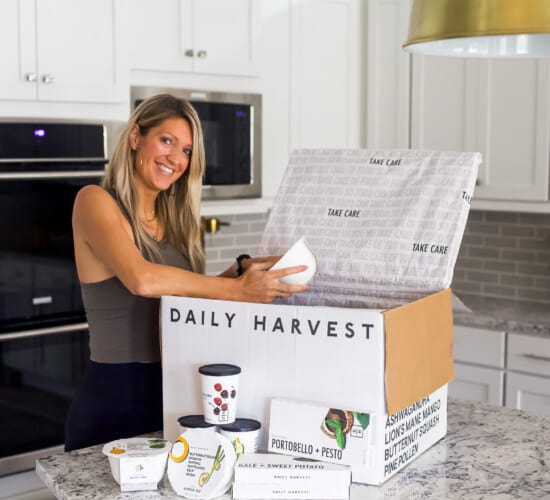 girl in workout clothes opening a daily harvest box