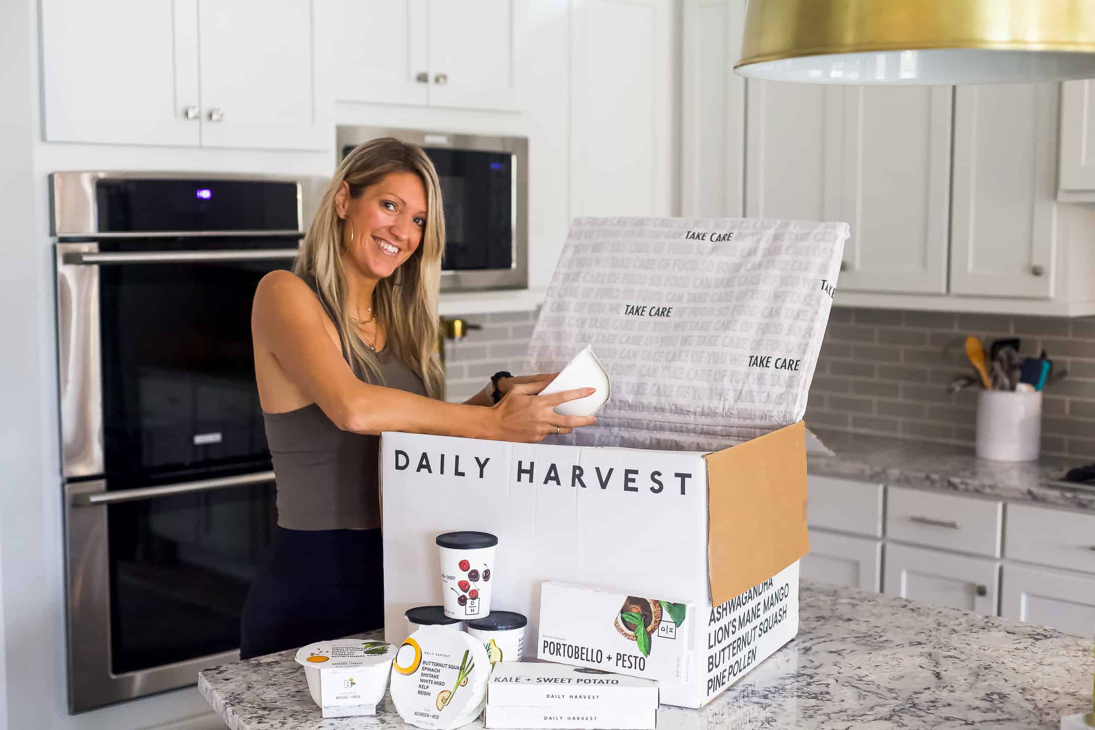 girl in workout clothes opening a daily harvest box