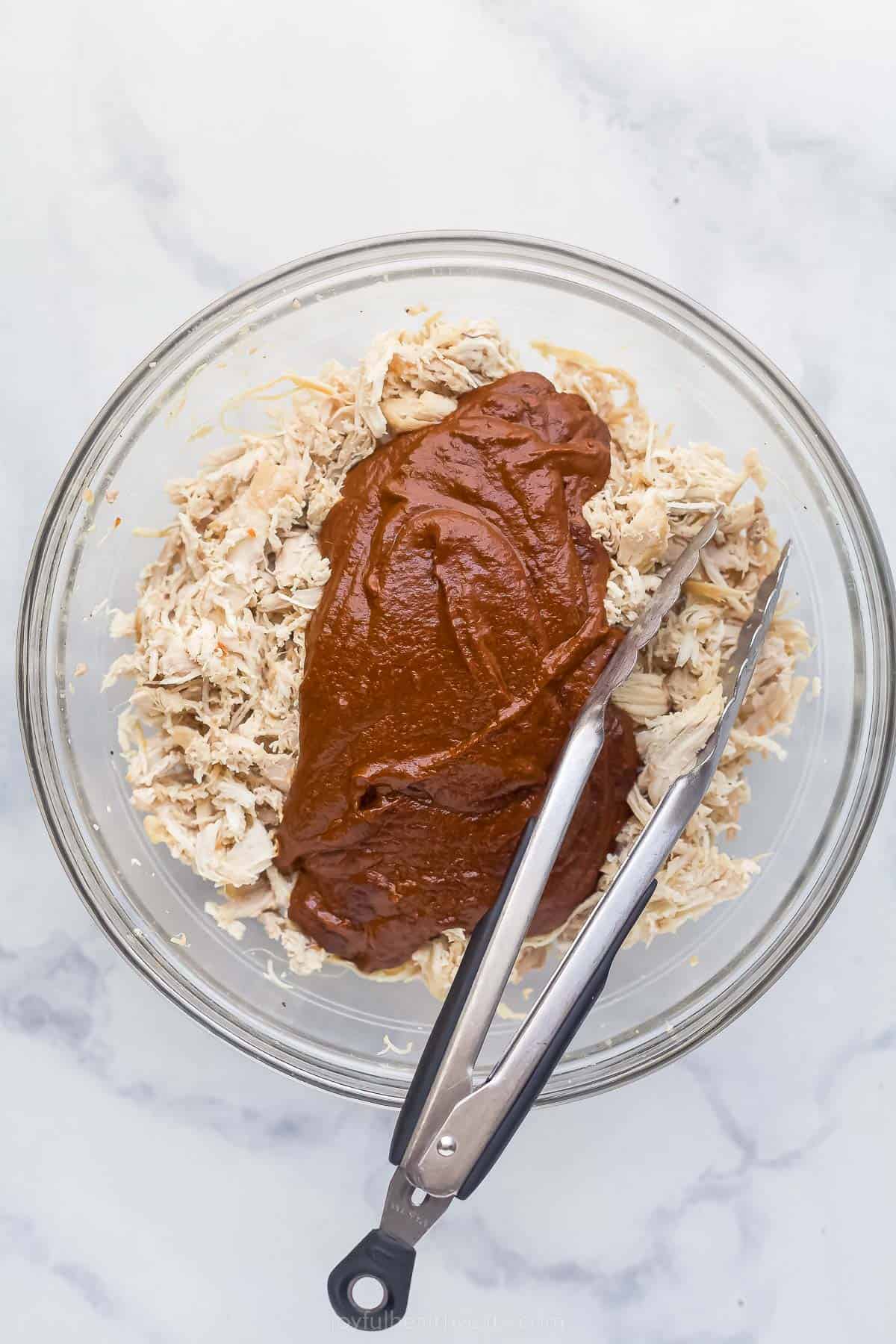 chicken mole sauce over a bowl of shredded chicken