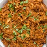 shredded chicken tossed in a dark red mole sauce topped with fresh herbs