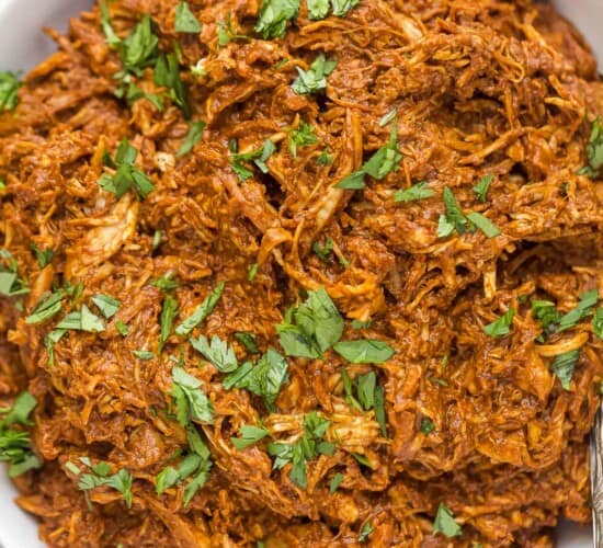 shredded chicken tossed in a dark red mole sauce topped with fresh herbs