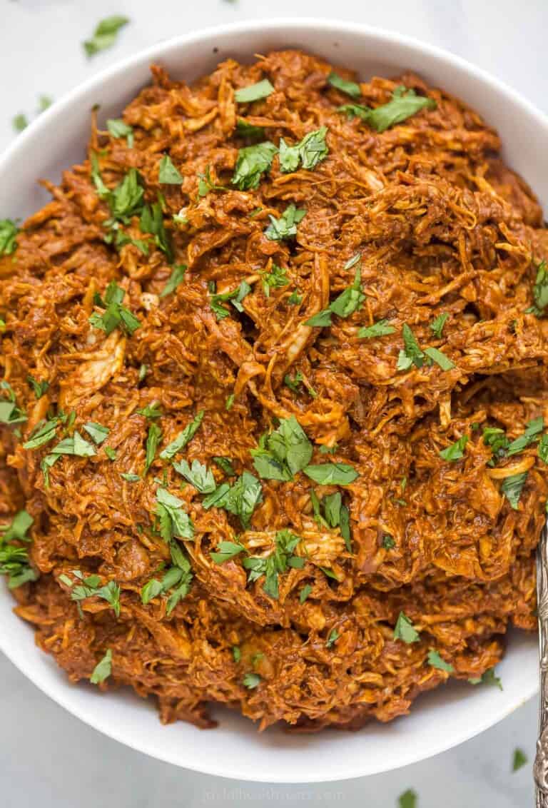 shredded chicken tossed in a dark red mole sauce topped with fresh herbs