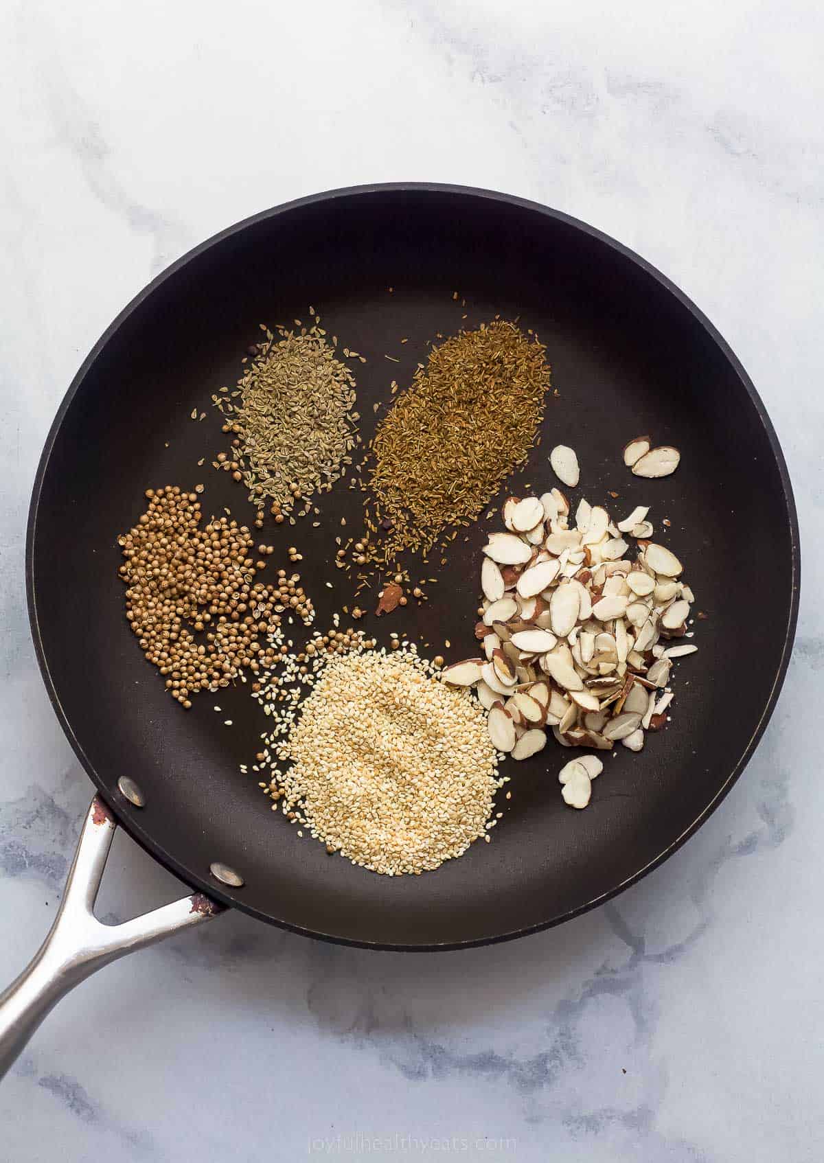 dried spices in a cast iron skillet and almonds about to be toasted