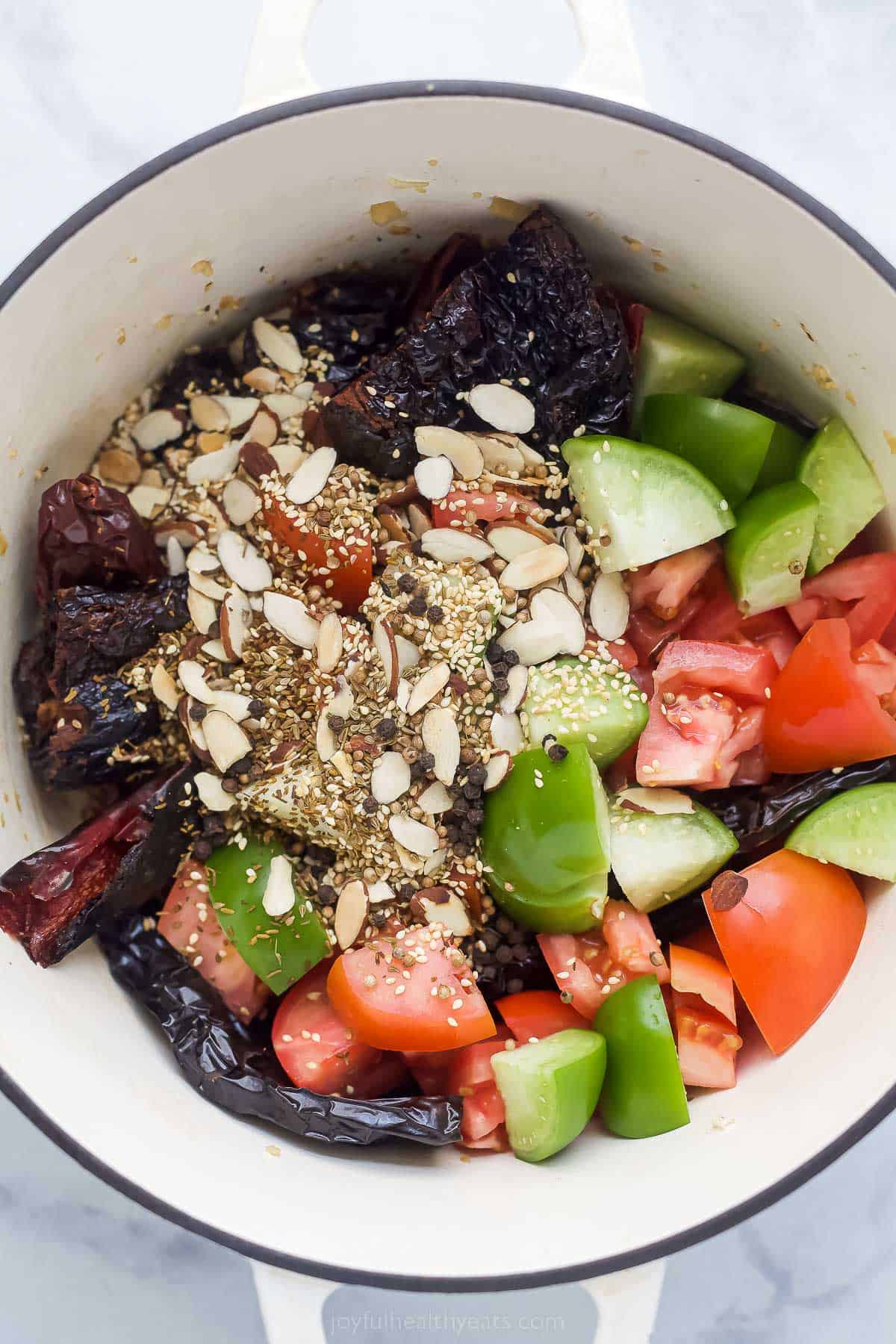 dried chilies, diced tomatillos, diced tomatoes, and other ingredients in a pot to make chicken mole