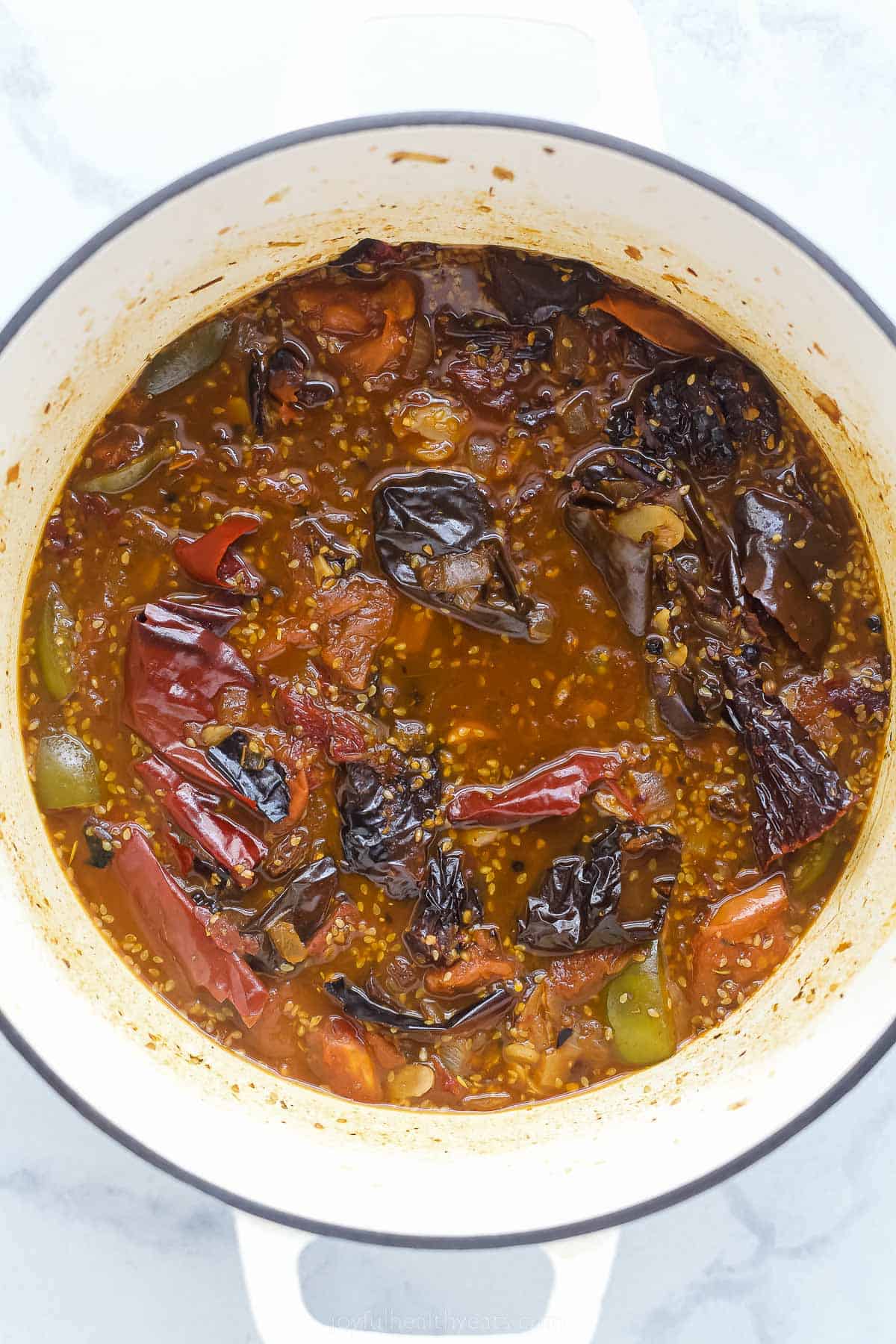 a dark colored base sauce with dried chilies, tomatoes, and ،es