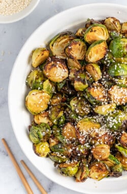 a bowl of asian-inspired brussels sprouts with sesame seed garnish