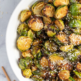 a bowl of asian-inspired brussels sprouts with sesame seed garnish