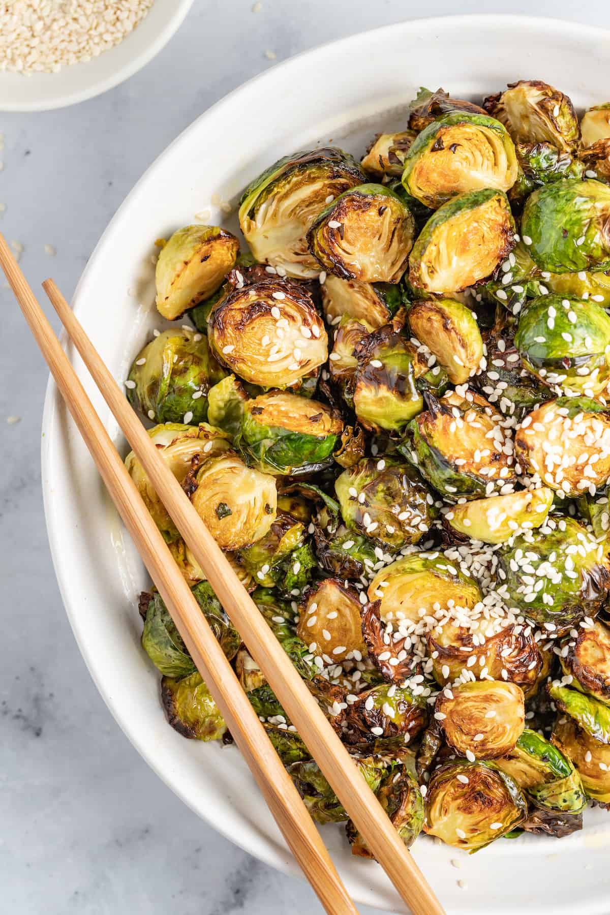 a bowl of crispy fried brussels sprouts and chopsticks