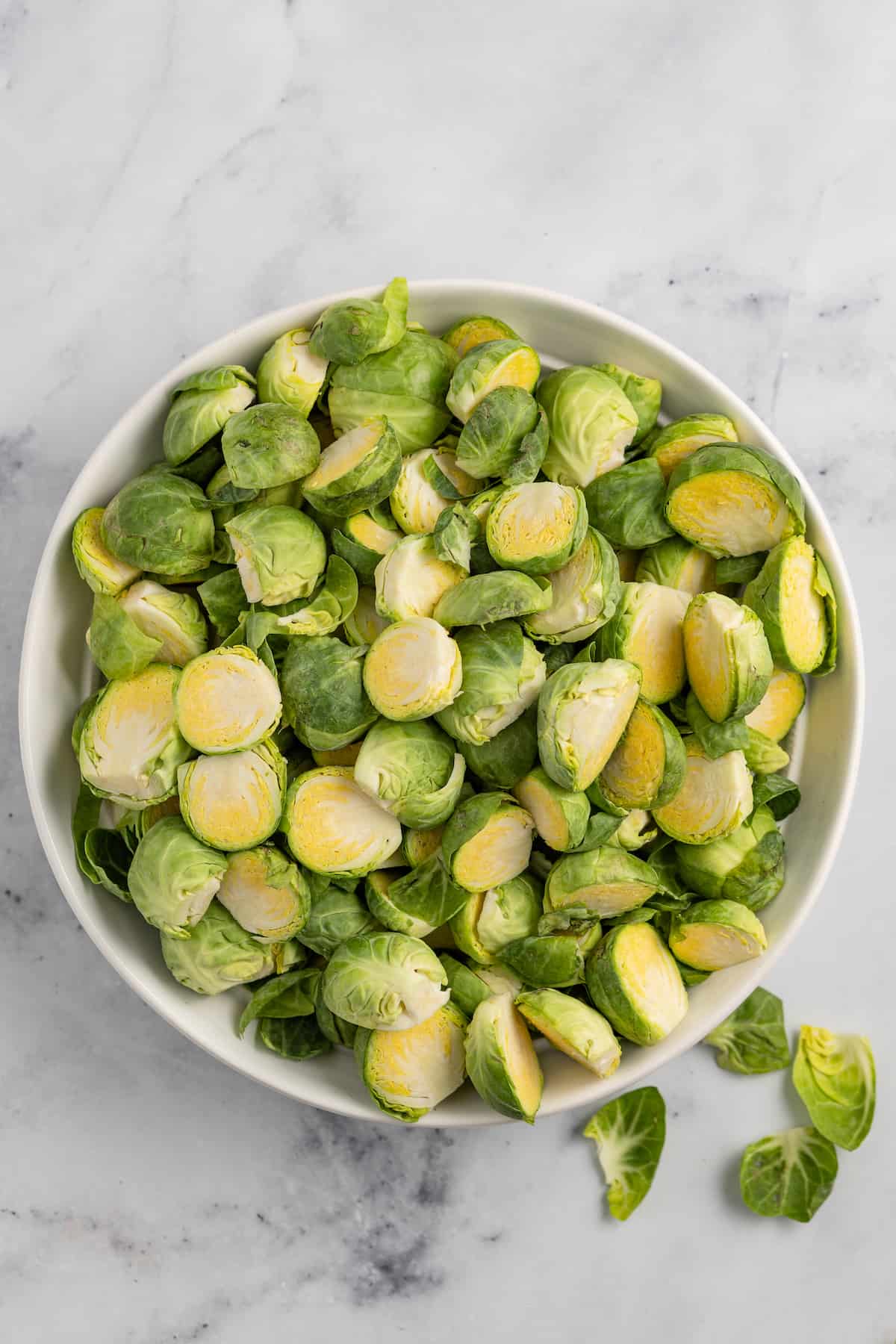 These Crispy Asian Air Fryer Brussels Sprouts are crunchy little bites filled with lots of soy, ginger, garlic, and spicy flavor. a large bowl of raw halved brussels sprouts