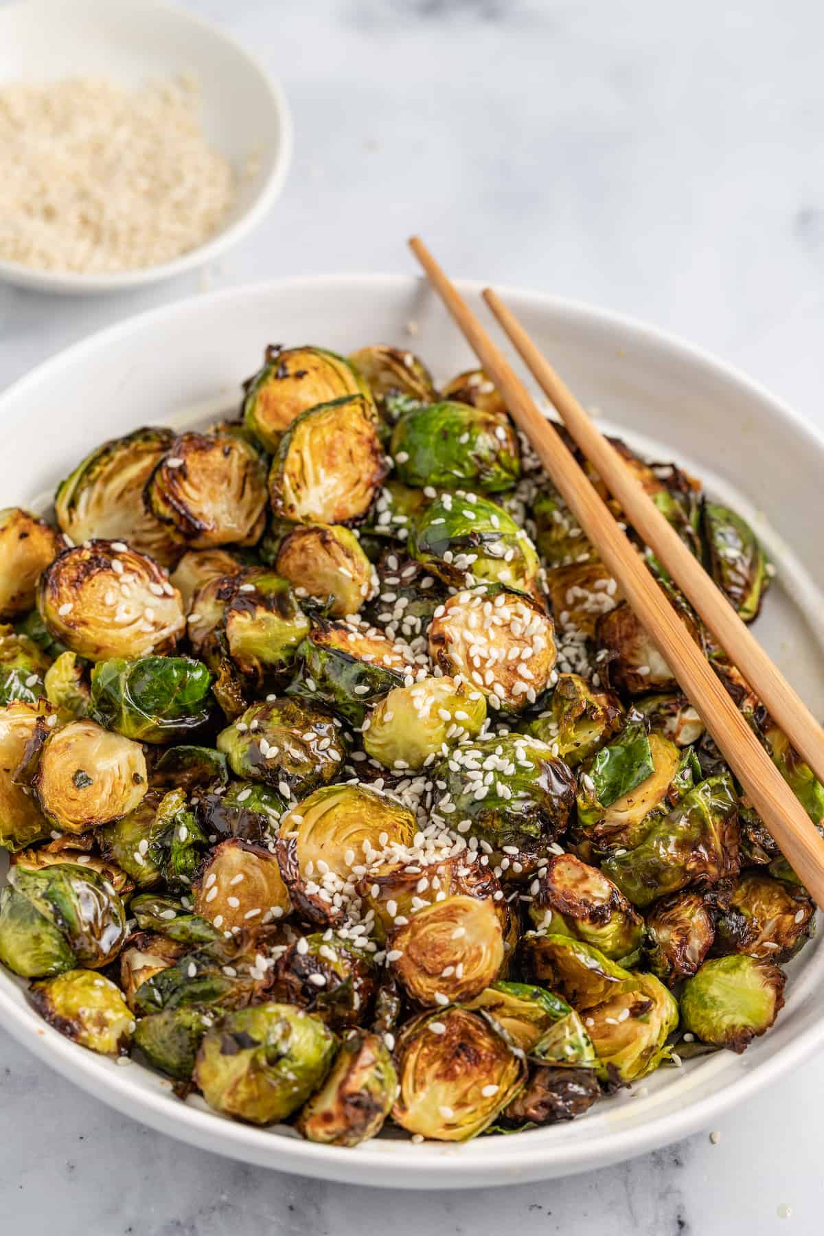 These Crispy Asian Air Fryer Brussels Sprouts are crunchy little bites filled with lots of soy, ginger, garlic, and spicy flavor. a bowl of crispy fried brussels sprouts
