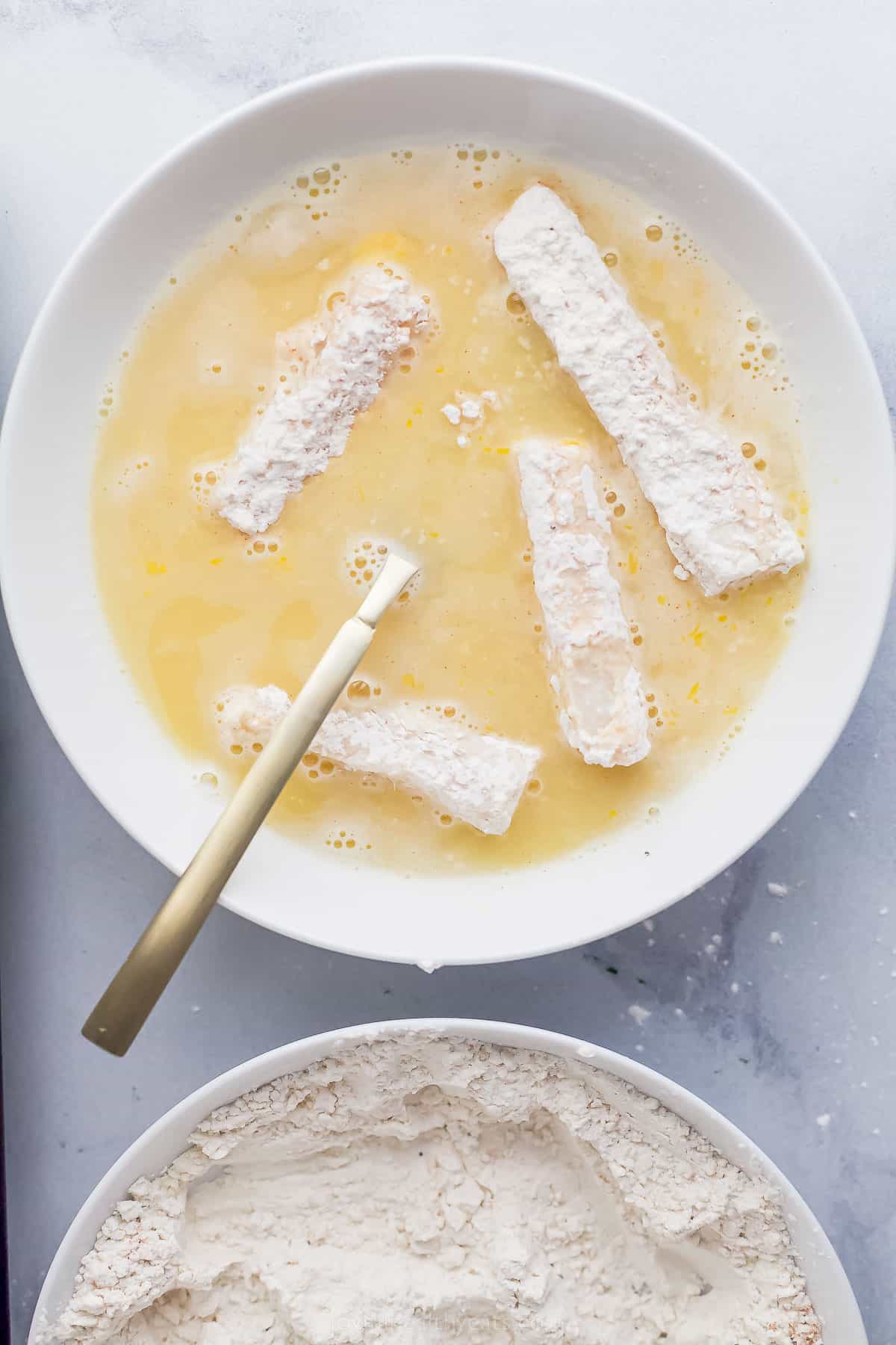 fish sticks being dipped into a beer batter