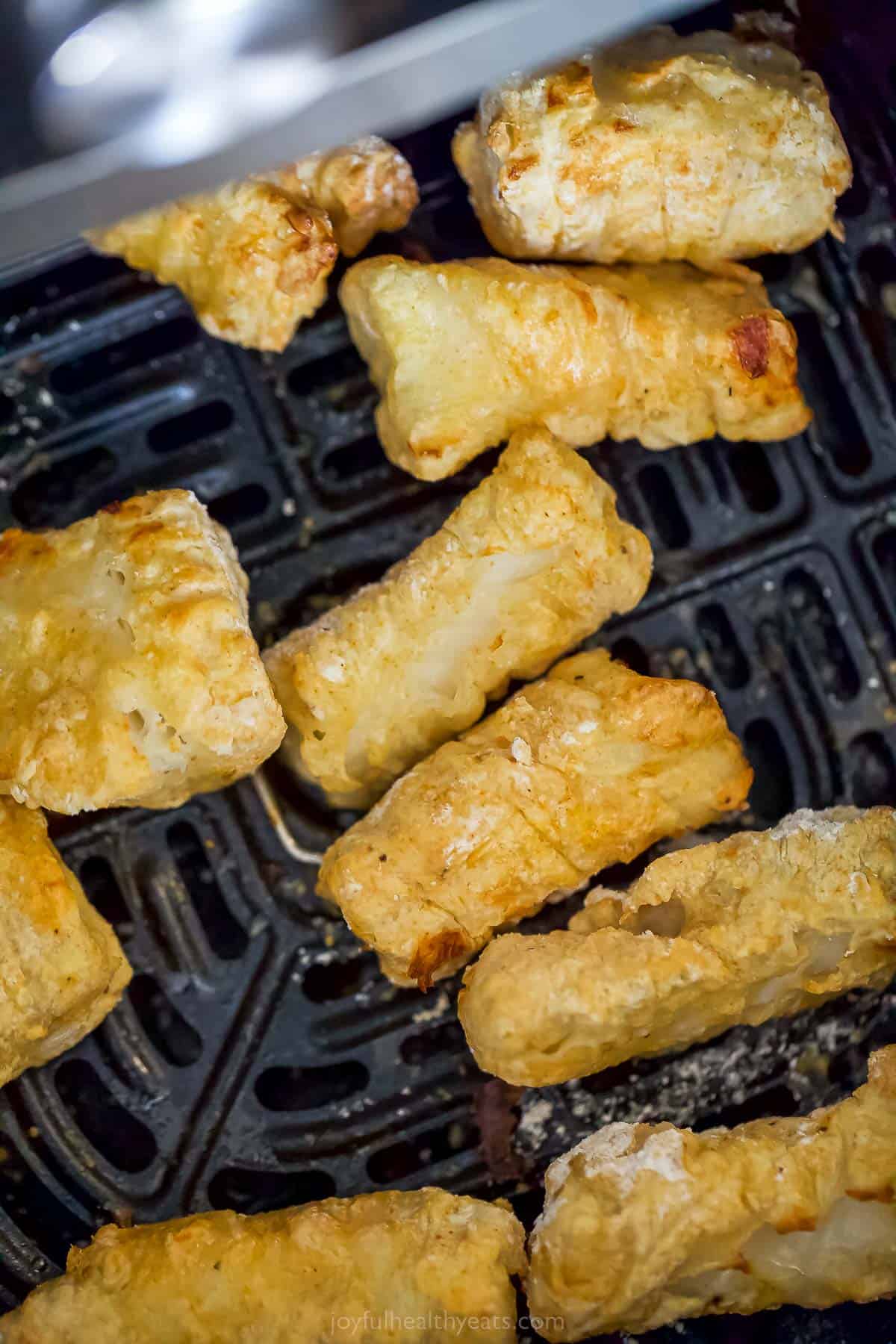 cod strips with a golden crust that are in an air fryer tray