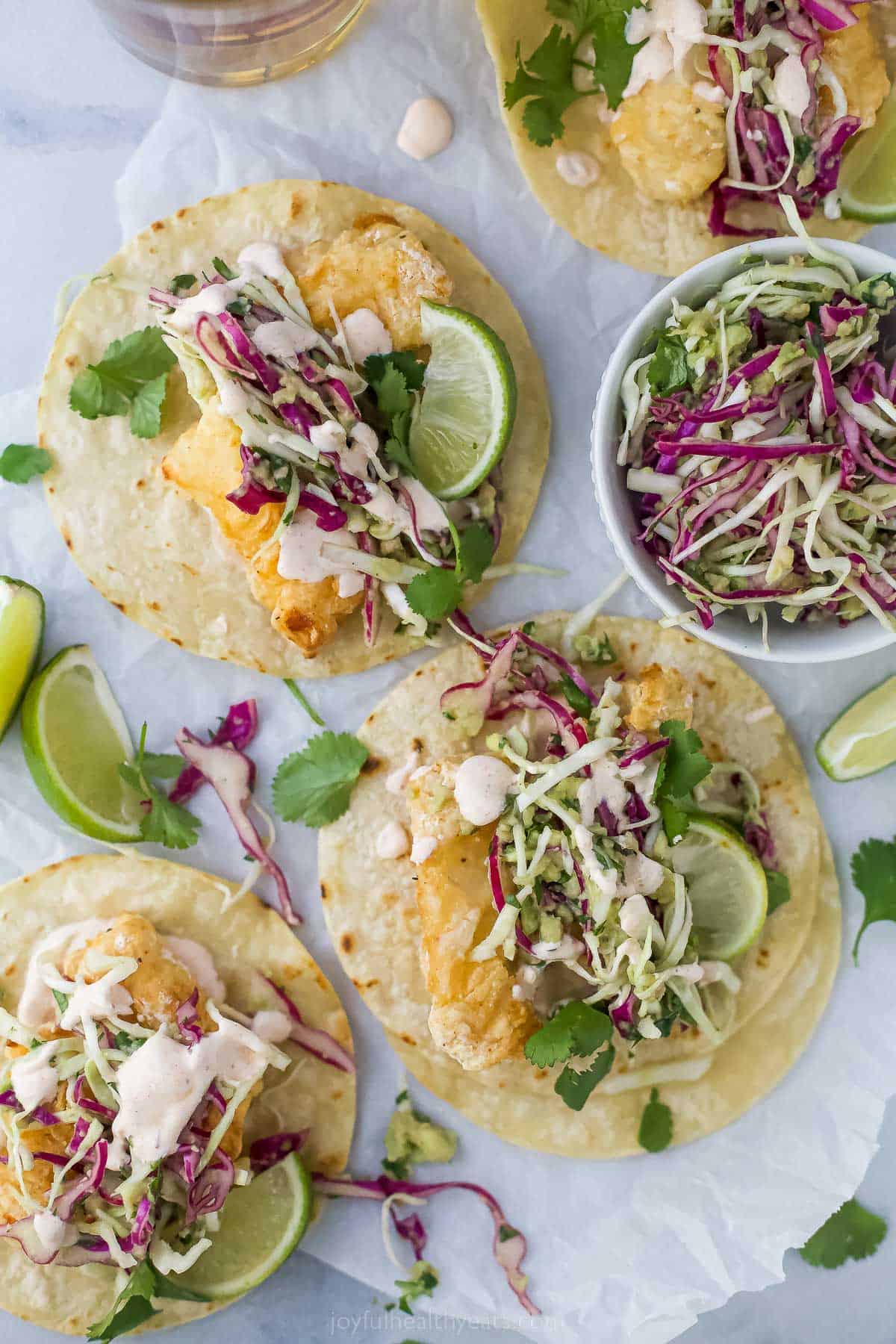 top view of air fryer beer battered fish tacos with slaw and lime wedge as a garnish