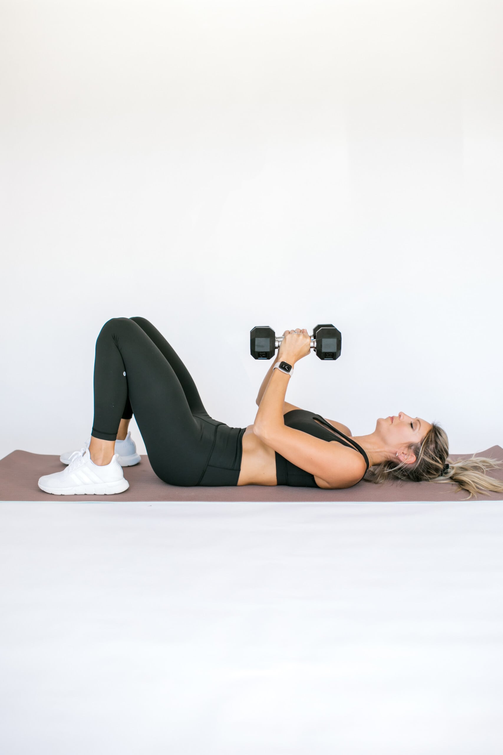 girl on the floor with dumbbells doing a chest press