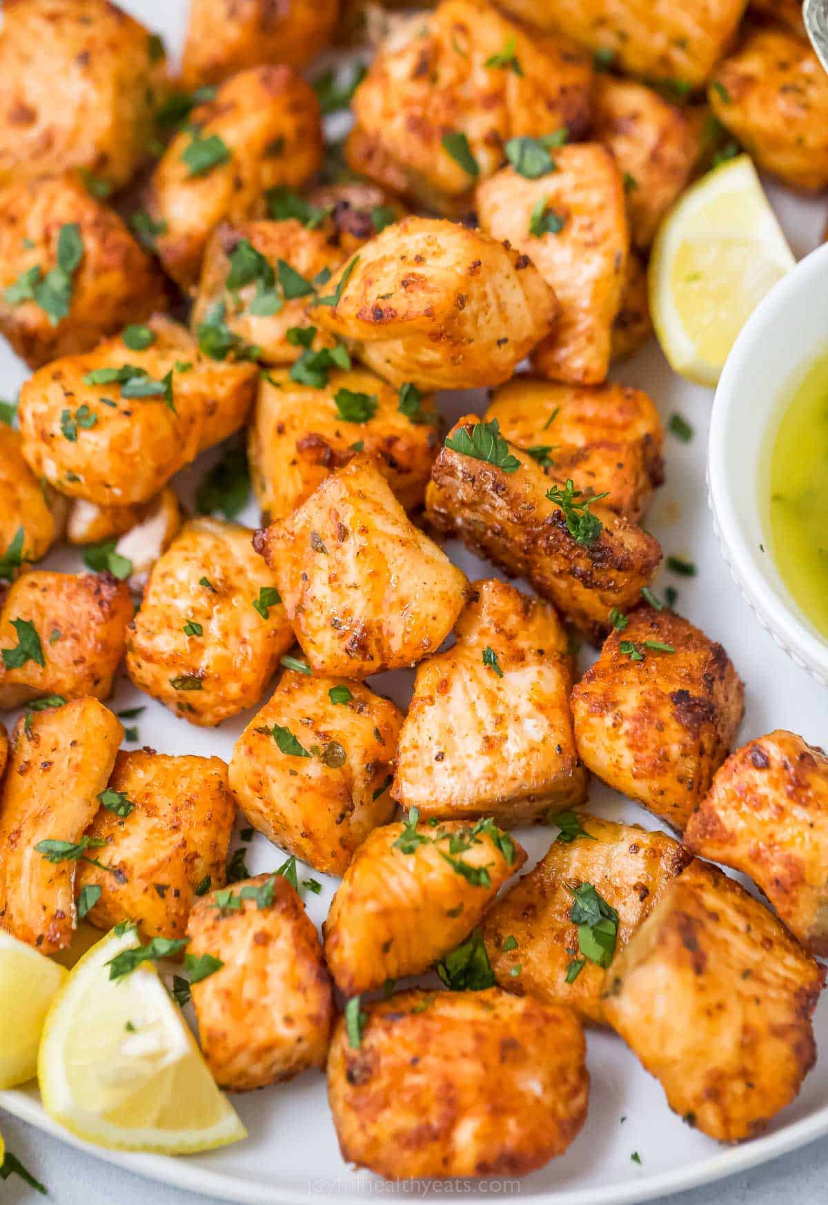 Close-up of air fryer salmon bites with a lemon wedge on the side. 