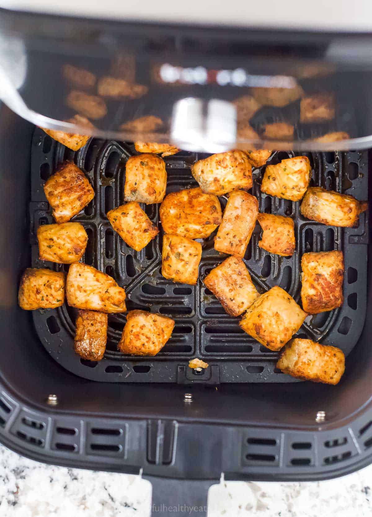 Cooked salmon bites in the air fryer basket. 