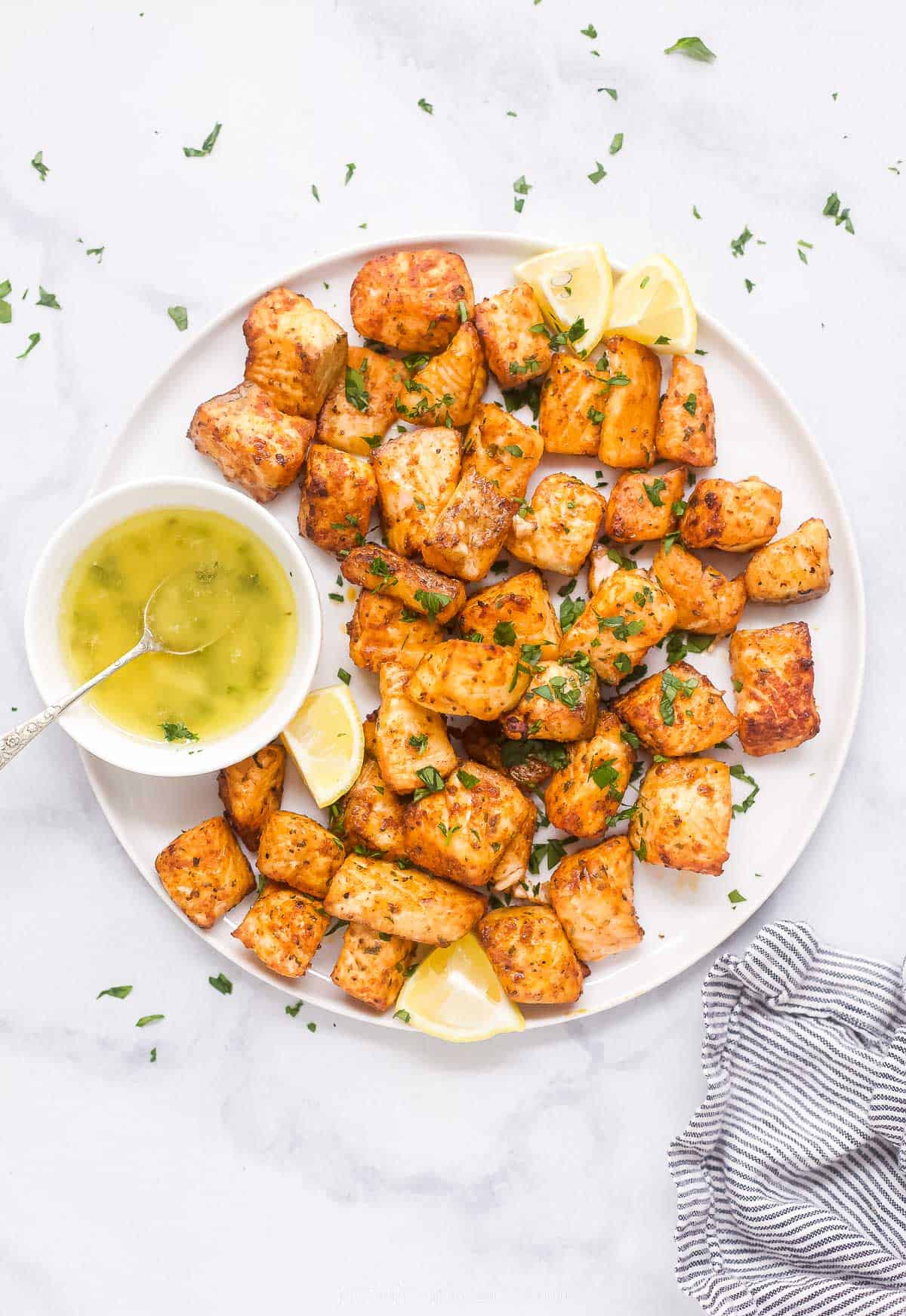 Overhead shot of air fryer salmon bites with honey butter on the side.