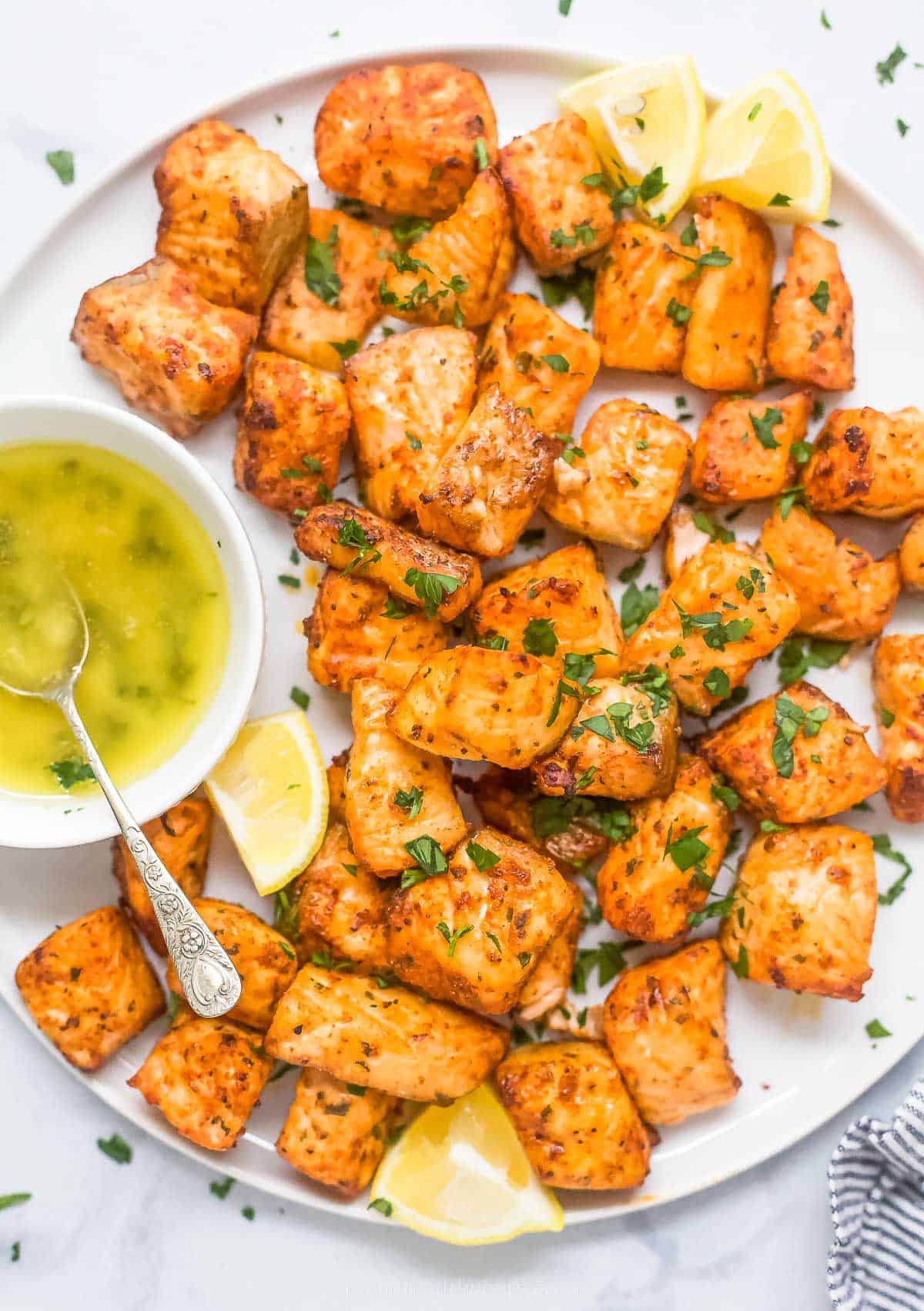Air fryer salmon bites with lemon wedges and ،ney ،er on the side. 