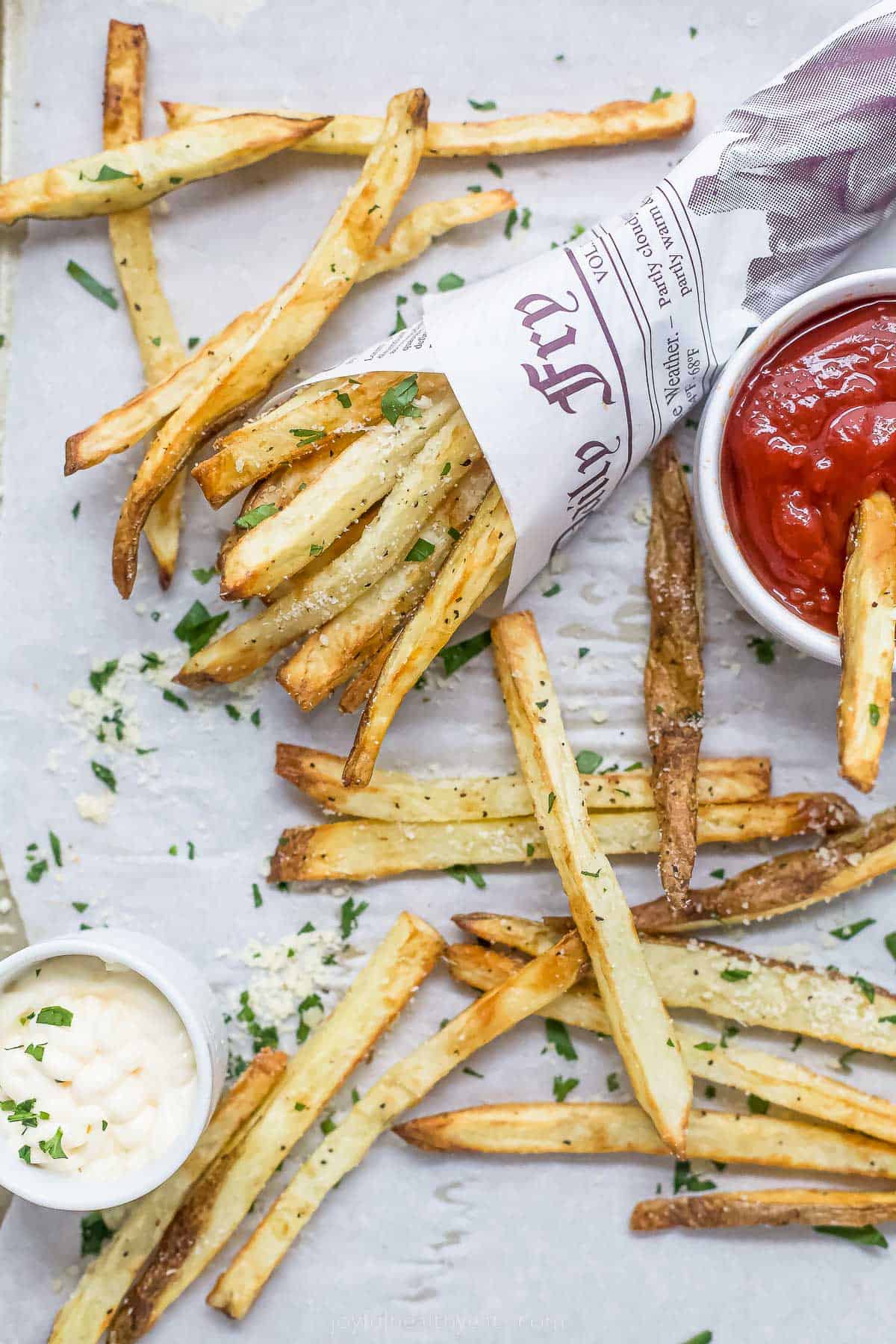 Pommes frites in a paper cone. Dipping sauces on the side. 