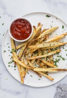 Pommes frites on a plate with ketchup on the side.