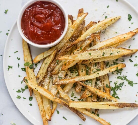 Pommes frites on a plate with ketchup on the side.