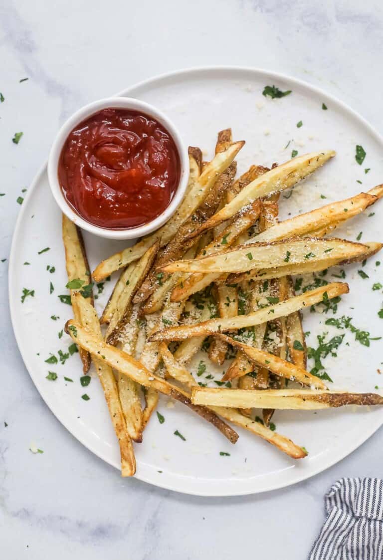 Pommes frites on a plate with ketchup on the side.