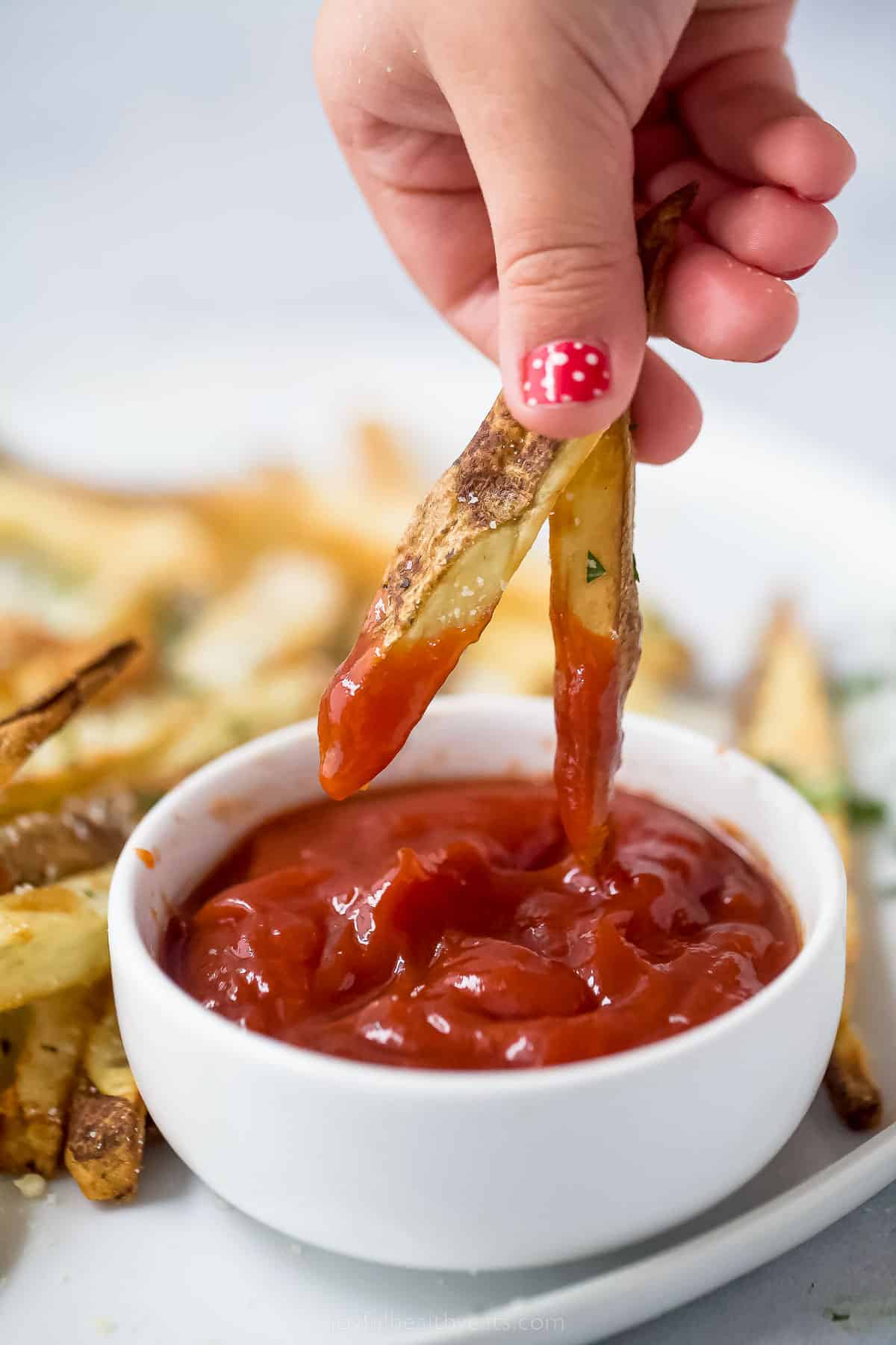 Dipping two pommes frites into ketchup. 