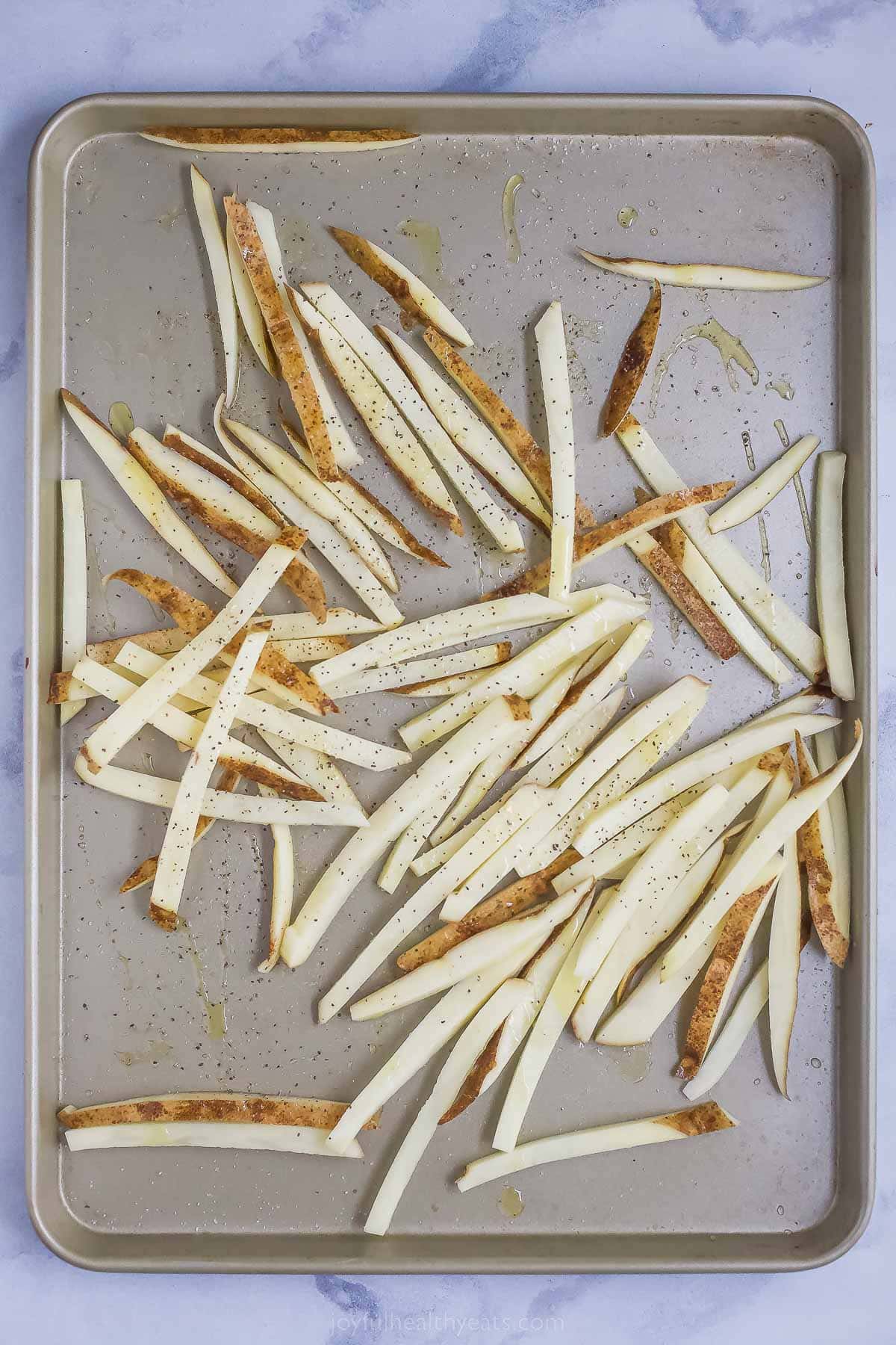 Tossing the fries in olive oil, salt, and pepper. 