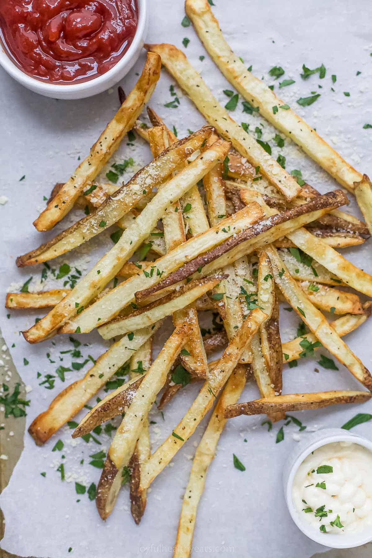 Pommes frites on a parchment lined tray with dipping sauces on the side. 