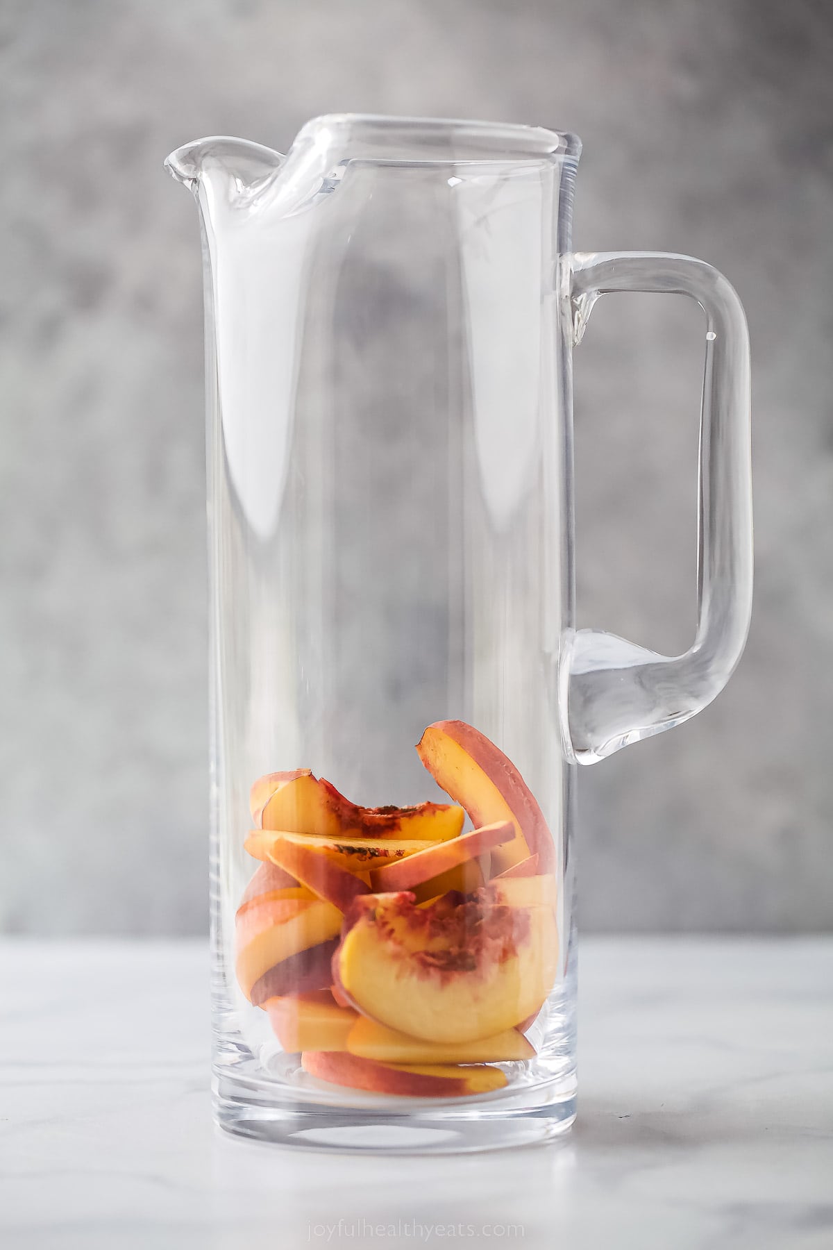 Adding the peaches to the pitcher.