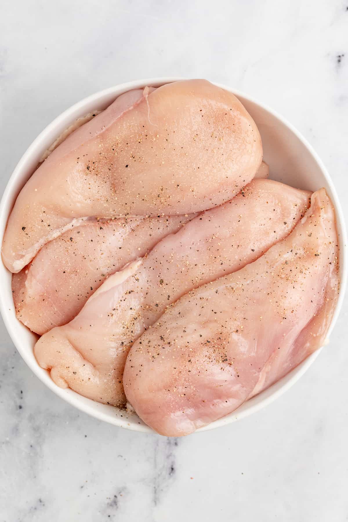 Seasoning the chicken with salt and pepper to taste.